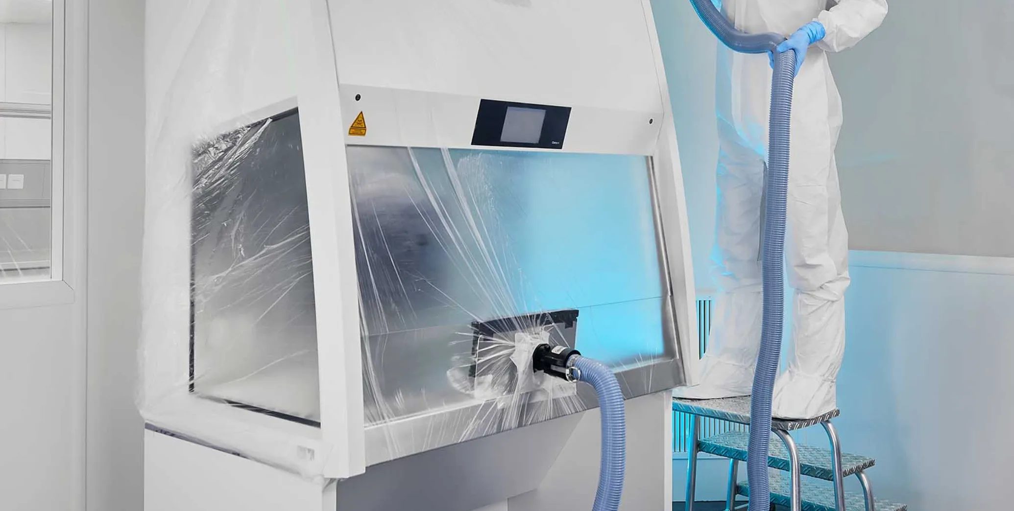 Tekniker vid isolator i renrum – biosäkerhetsskåp med HEPA-filtrering för mikrobiologisk provtagning